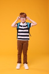 Happy schoolboy in glasses on orange background