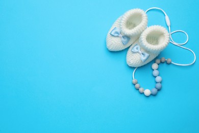 Photo of Cute baby booties and toy on light blue background, flat lay. Space for text