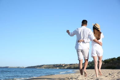Photo of Lovely couple walking on beach, back view. Space for text