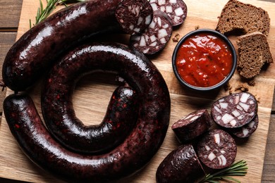 Photo of Tasty blood sausages served on wooden table, flat lay