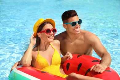 Photo of Happy couple with inflatable ring in swimming pool. Summer vacation