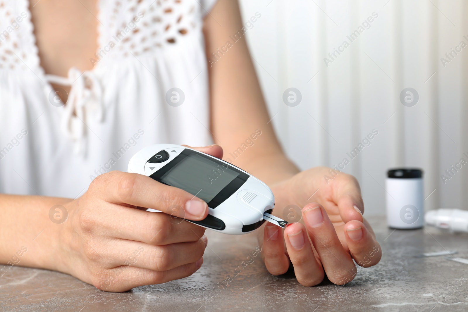 Photo of Woman checking blood sugar level with glucometer at table. Diabetes test