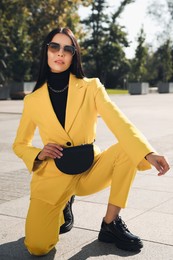 Photo of Beautiful young woman with stylish waist bag on city street