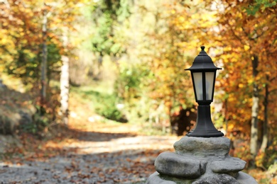 Metal lantern and blurred autumn park on background. Space for text