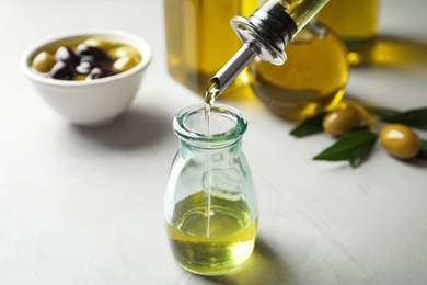 Photo of Pouring fresh olive oil into bottle on table