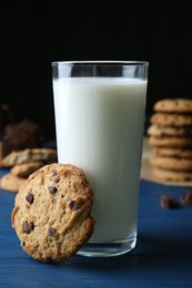 Photo of Tasty chocolate chip cookies and glass of milk on blue wooden table