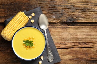 Delicious creamy corn soup served on wooden table, top view. Space for text