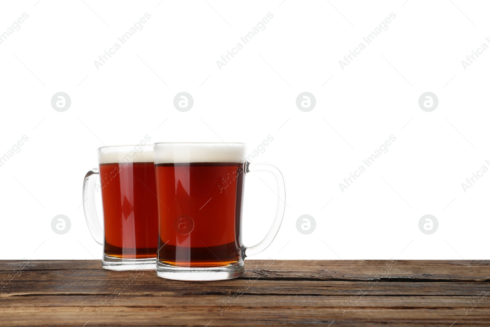 Photo of Glass mugs of delicious kvass on wooden table, white background