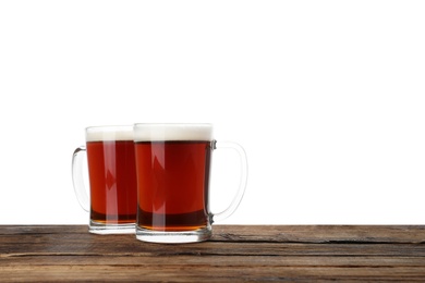 Photo of Glass mugs of delicious kvass on wooden table, white background