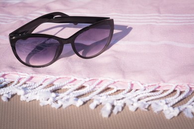 Photo of Stylish sunglasses and blanket on sunny day, closeup. Space for text