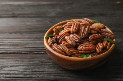 Photo of Dish with tasty pecan nuts on wooden table