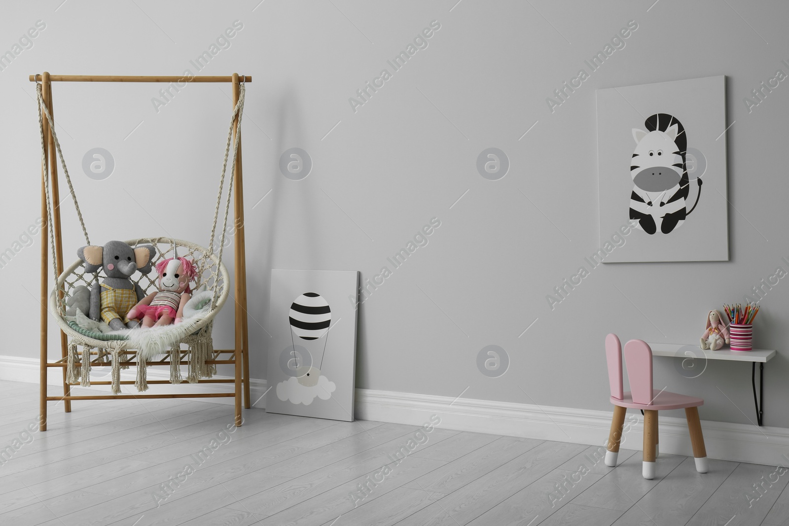 Photo of Stylish child's room interior with adorable paintings and hanging chair