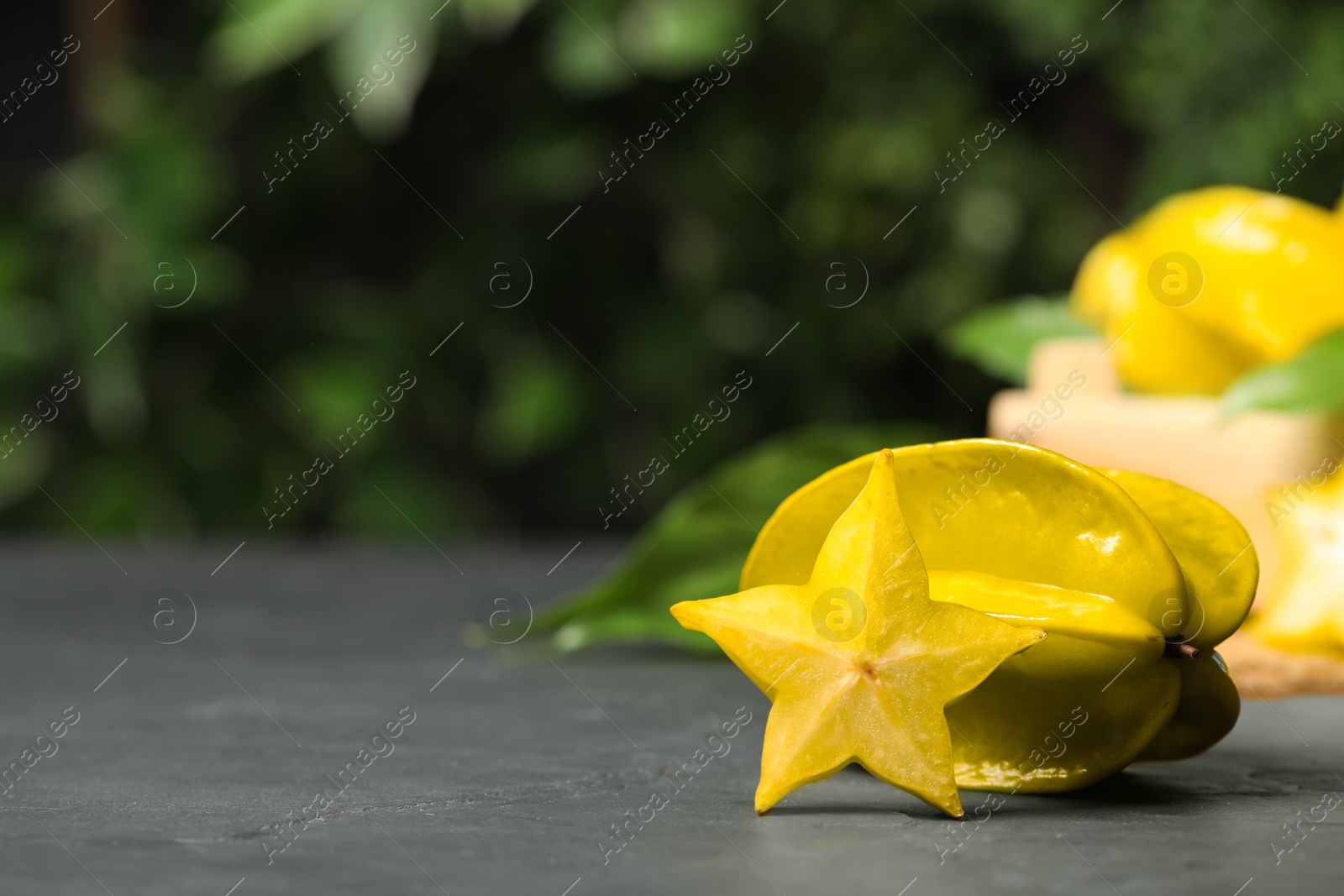 Photo of Delicious carambola and slice on black table. Space for text