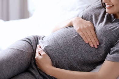 Young pregnant woman lying on bed at home