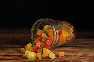 Overturned jar with mix of delicious candied fruits on wooden table