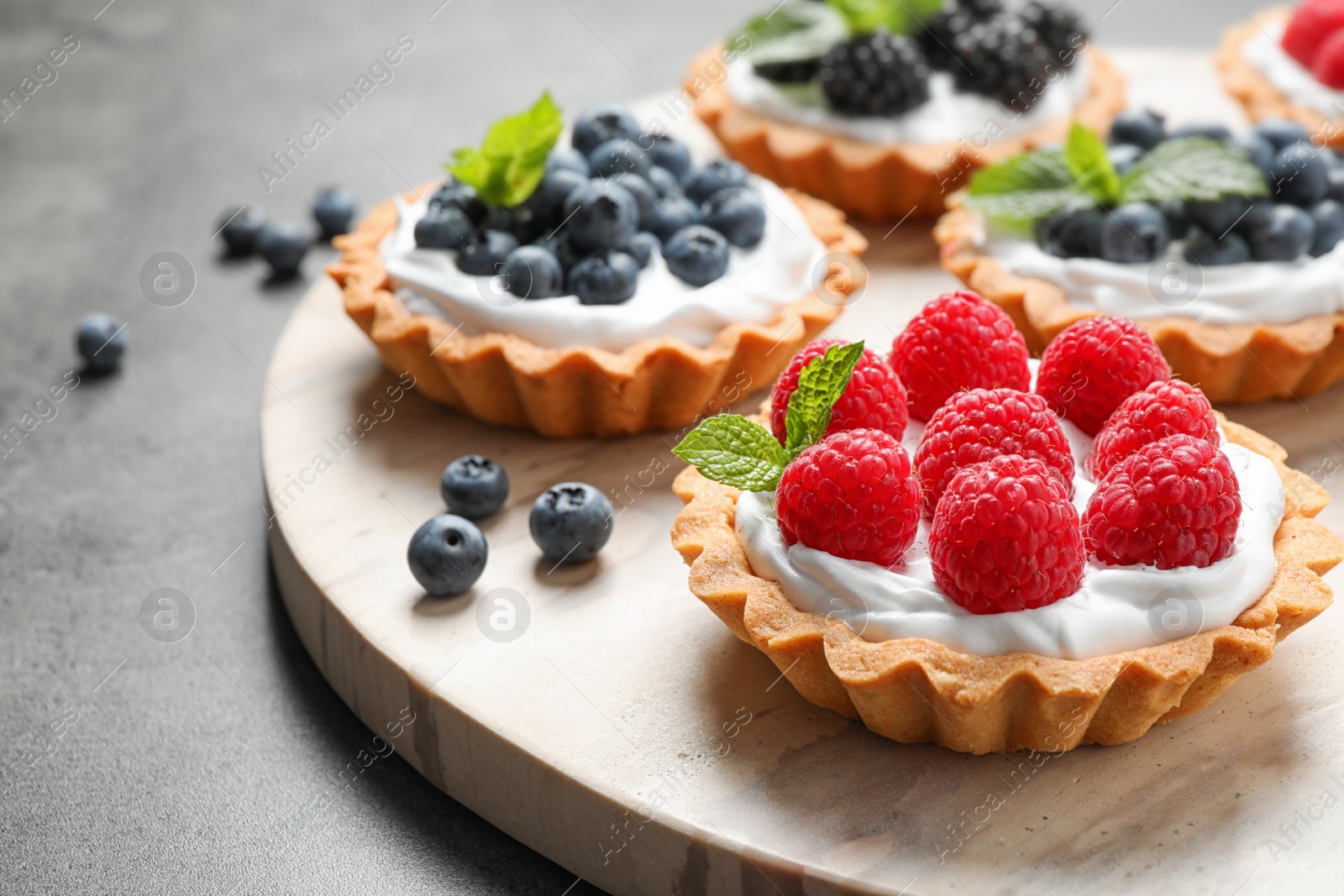 Photo of Different berry tarts on light table. Delicious pastries