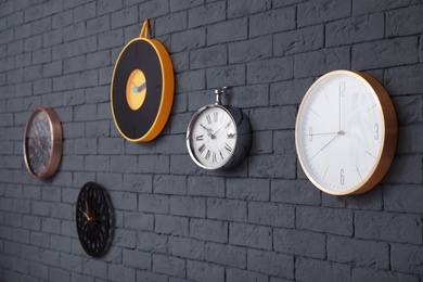 Photo of Different clocks on brick wall. Time concept