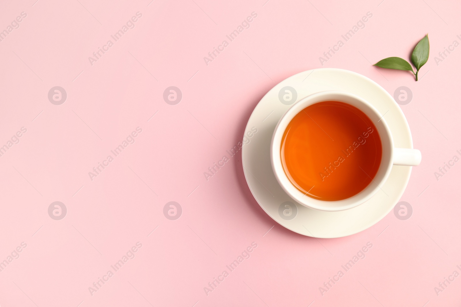 Photo of Cup of delicious tea with green leaves on color background, top view