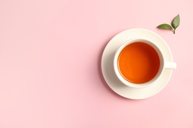 Photo of Cup of delicious tea with green leaves on color background, top view