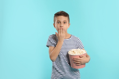 Photo of Emotional boy with popcorn during cinema show on color background