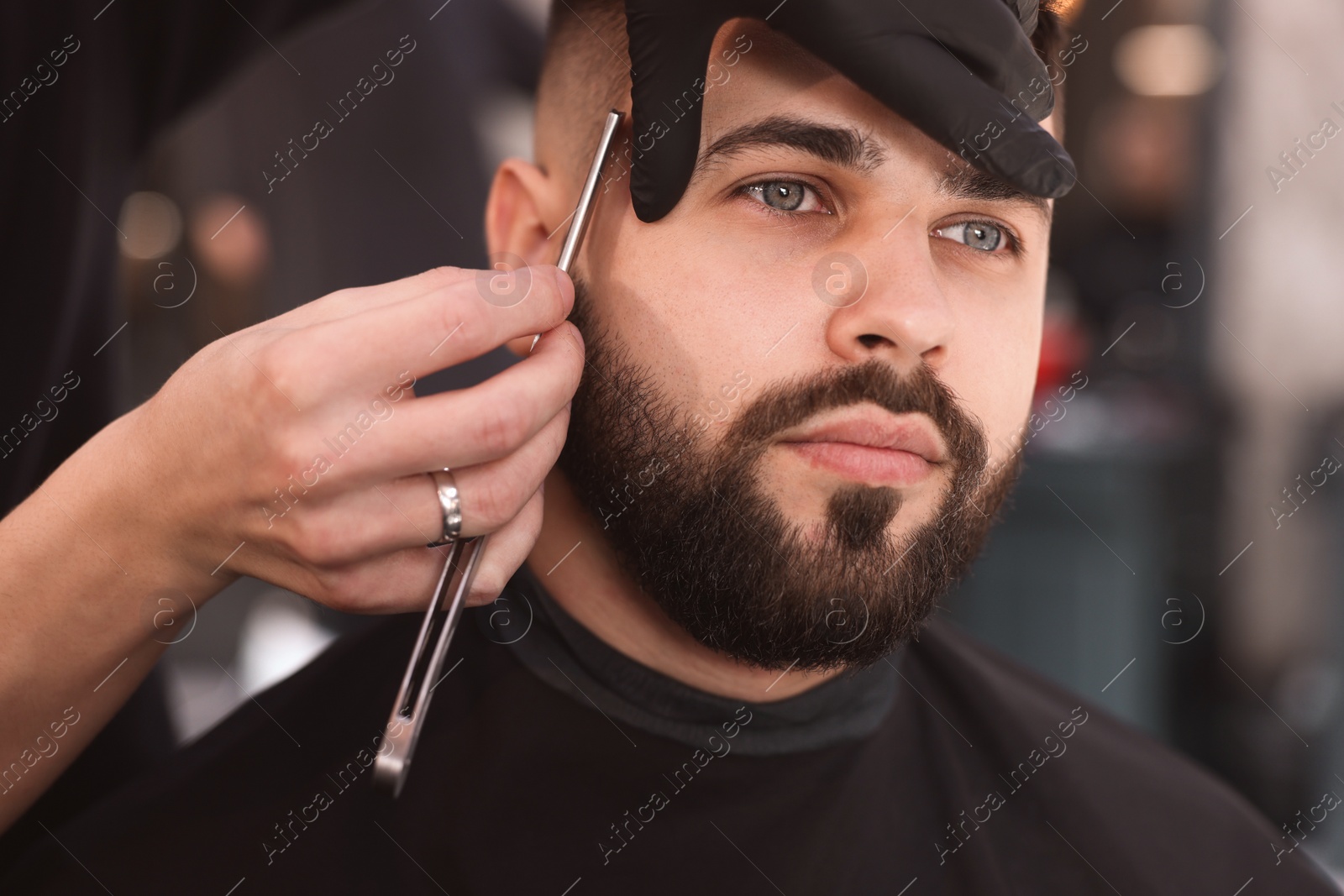 Photo of Professional hairdresser working with client in barbershop, closeup