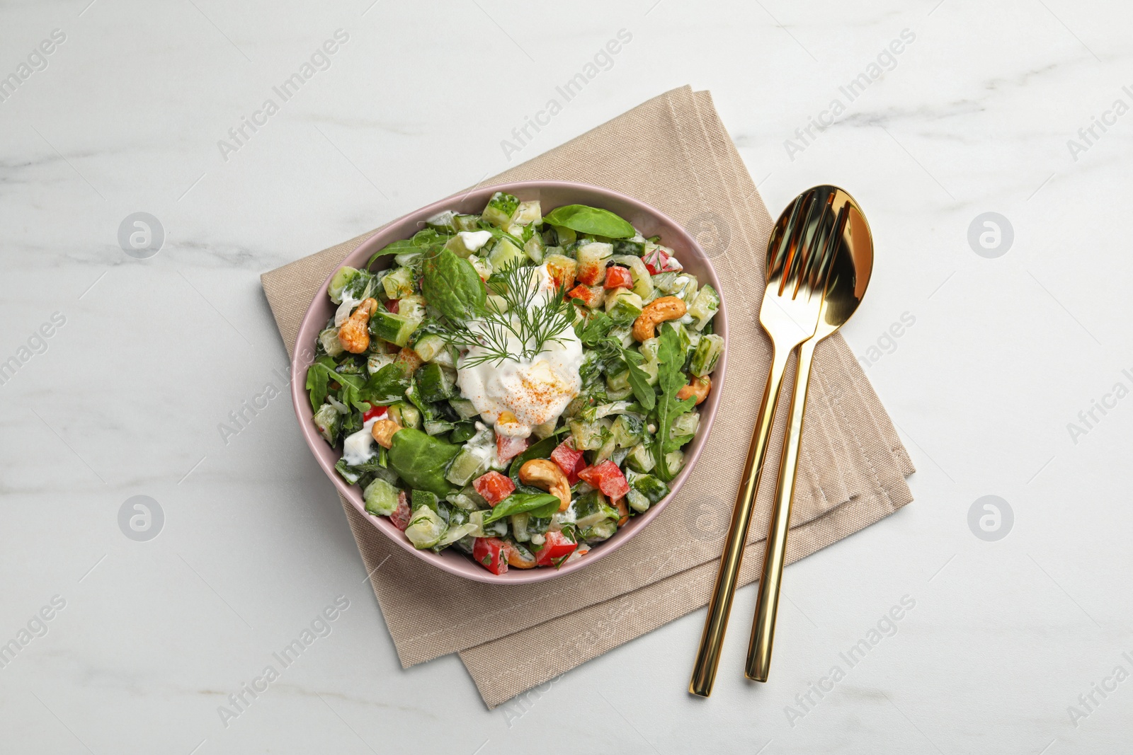 Photo of Bowl of delicious cucumber salad served on white marble table, flat lay