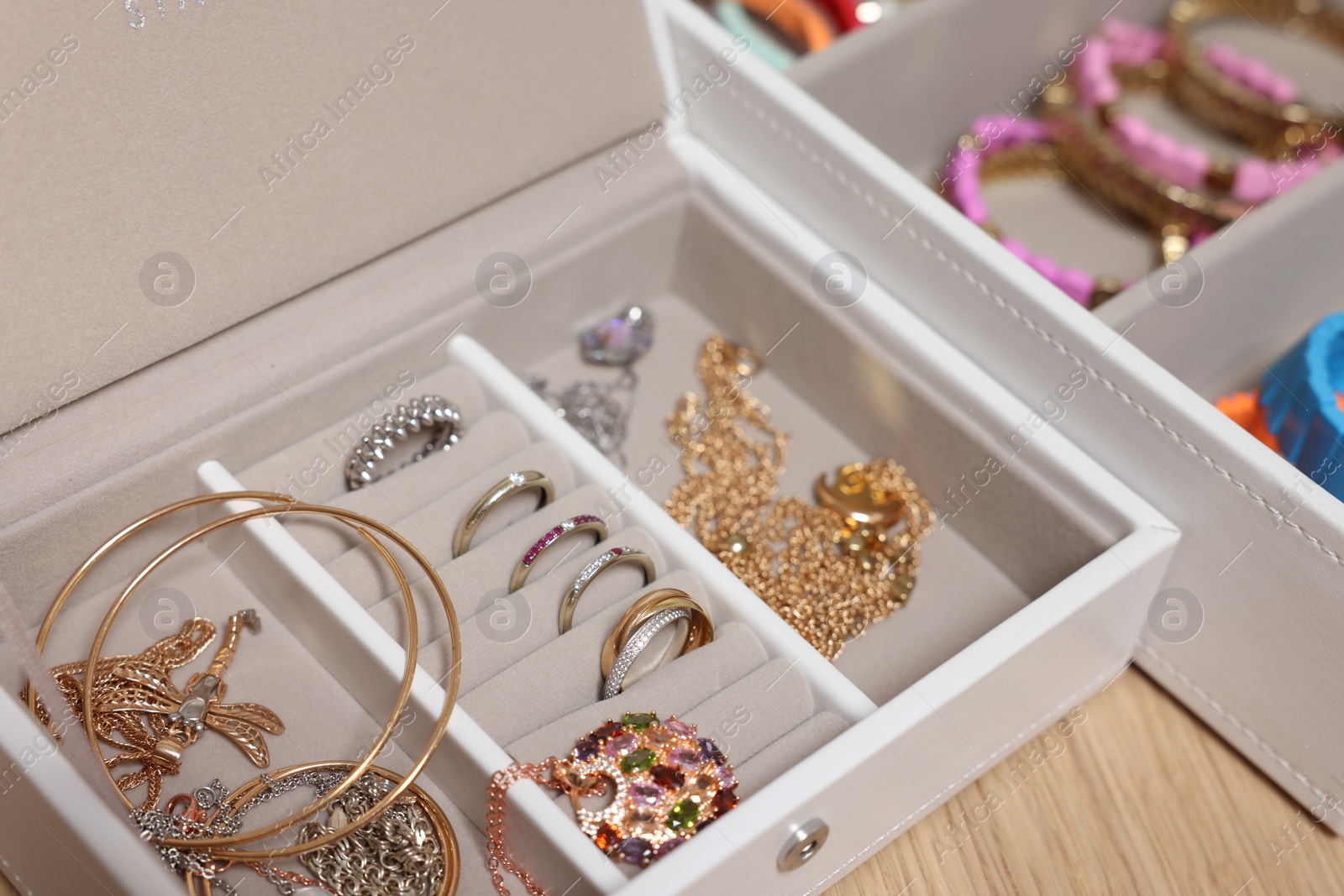 Photo of Jewelry boxes with stylish bracelets and other accessories on wooden table, closeup