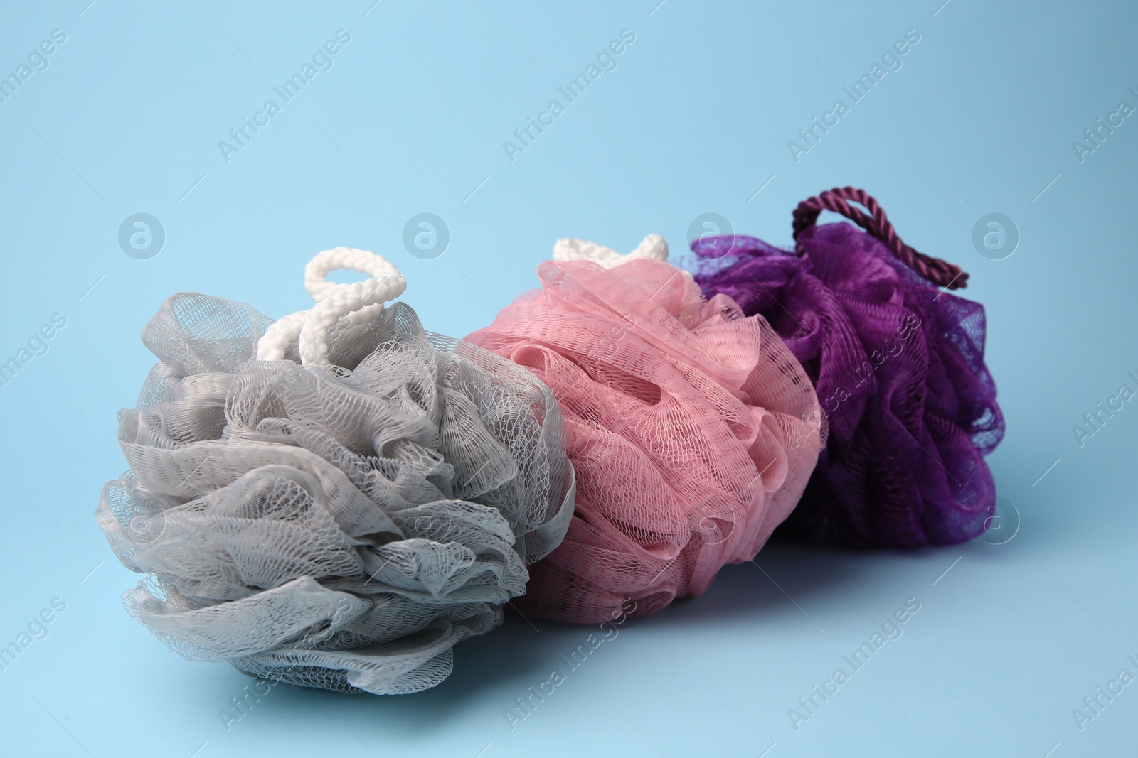 Photo of Colorful shower puffs on light blue background