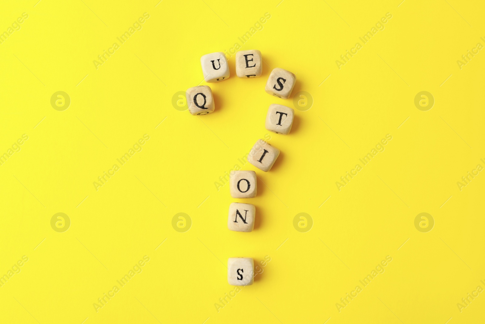 Photo of Wooden cubes with word QUESTIONS on yellow background, flat lay