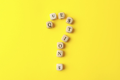 Wooden cubes with word QUESTIONS on yellow background, flat lay