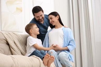 Photo of Happy pregnant woman spending time with her son and husband at home, low angle view
