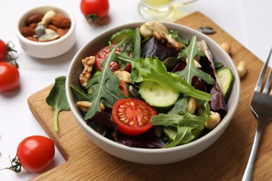 Photo of Tasty fresh vegetarian salad and ingredients on white table, closeup