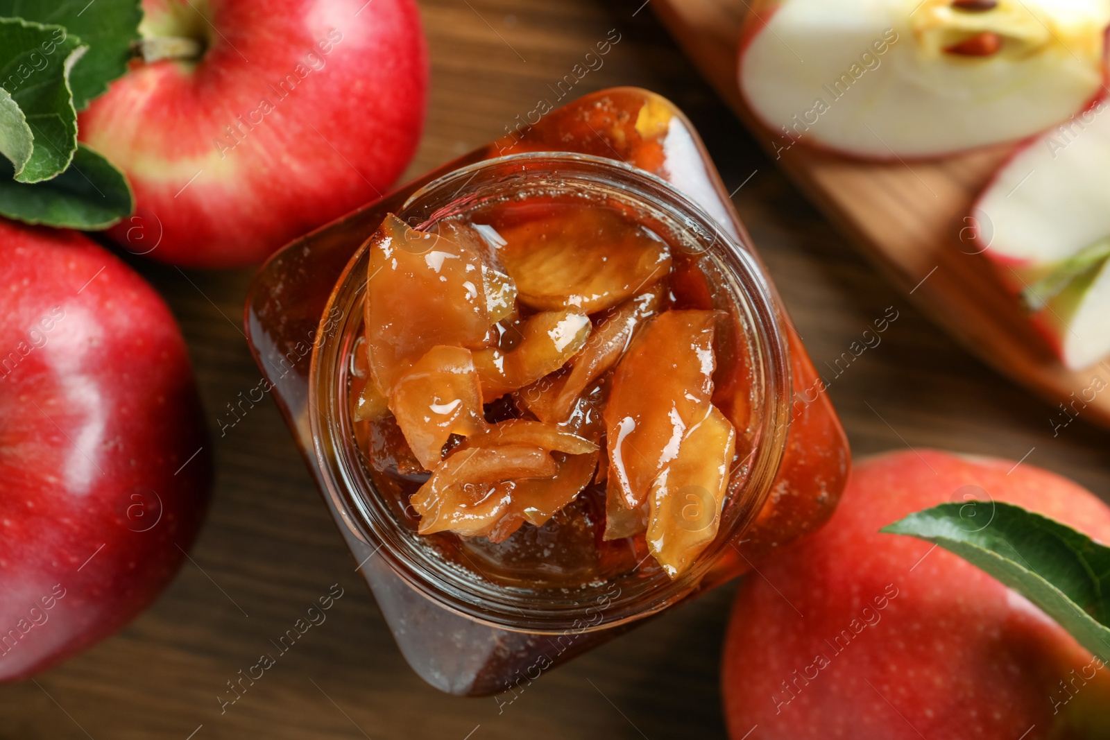 Photo of Tasty apple jam in glass jar and fresh fruits on wooden table, flat lay