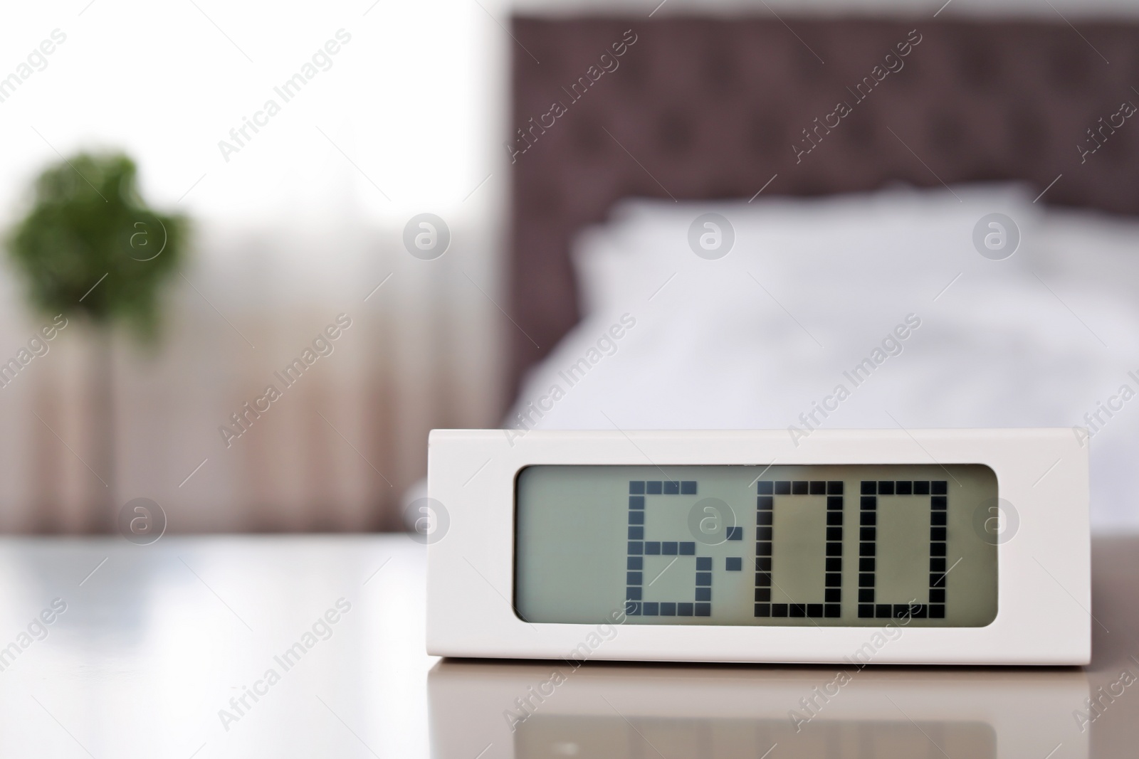 Photo of Digital alarm clock on table in bedroom. Time to wake up