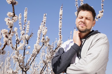 Man suffering from seasonal allergy outdoors, space for text