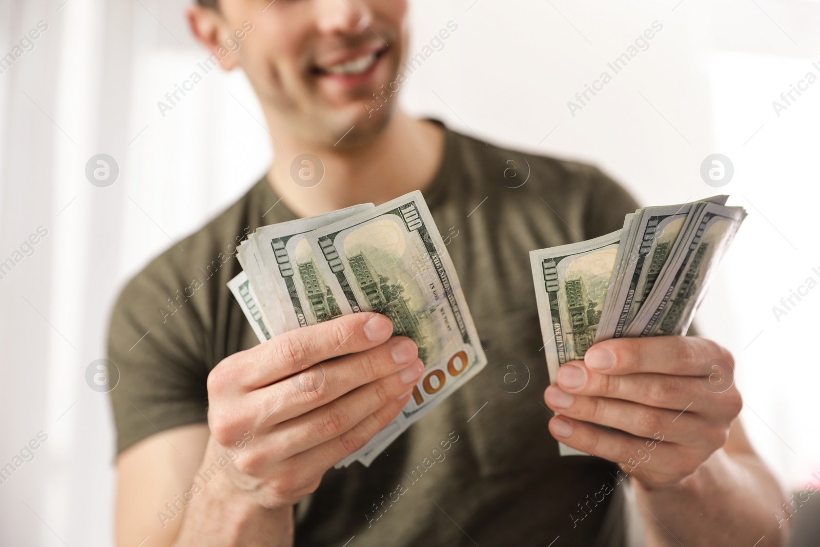 Photo of Young man counting money on blurred  background, closeup