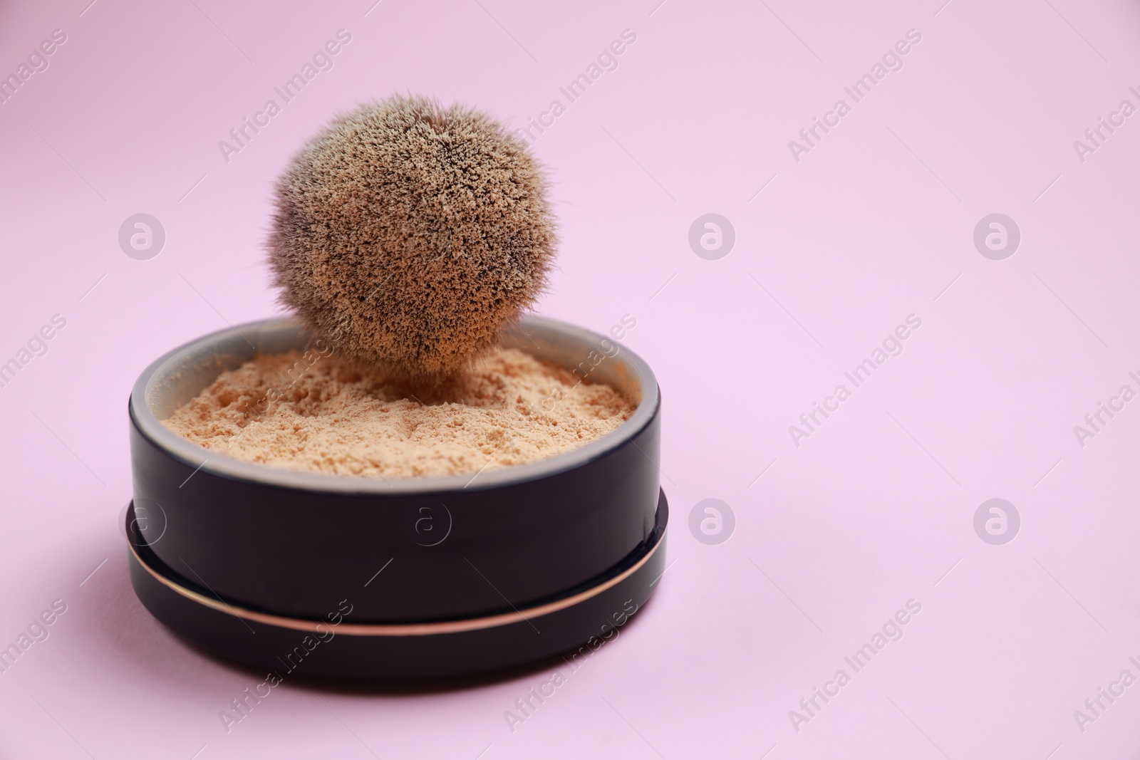 Photo of Face powder and brush on pink background, closeup. Space for text