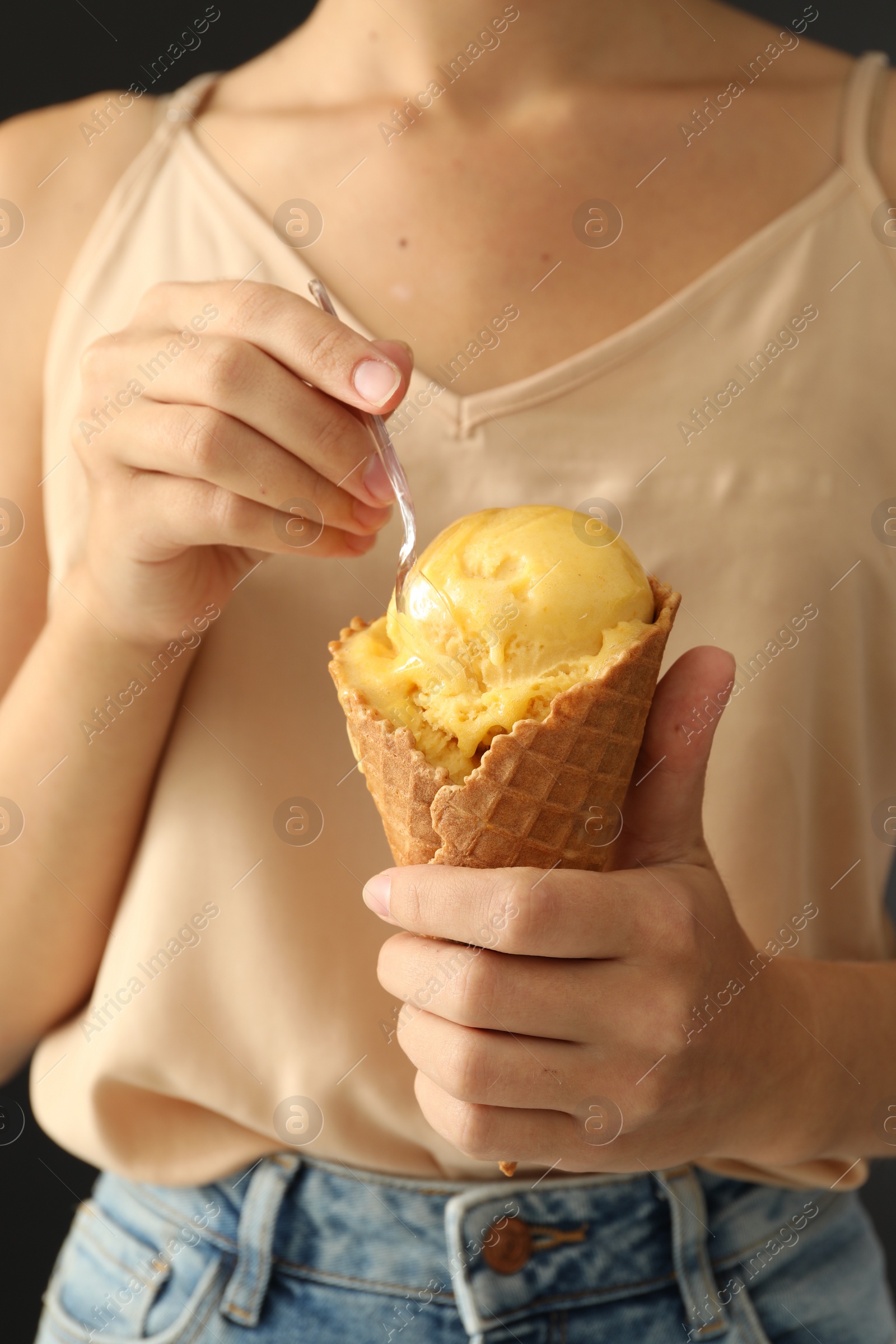 Photo of Woman eating yellow ice cream in wafer cone, closeup