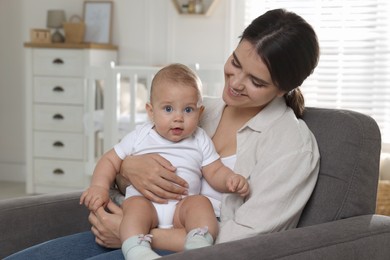 Photo of Happy young mother with her baby in armchair at home