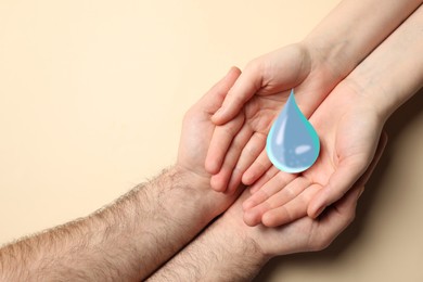 Image of Couple holding water drop on beige background, top view