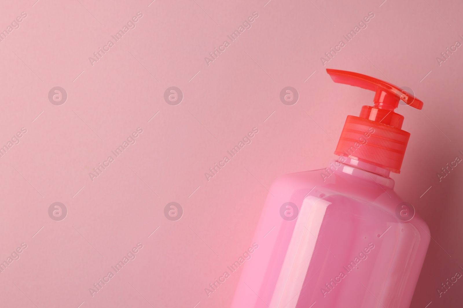 Photo of Bottle of liquid soap on pink background, top view. Space for text