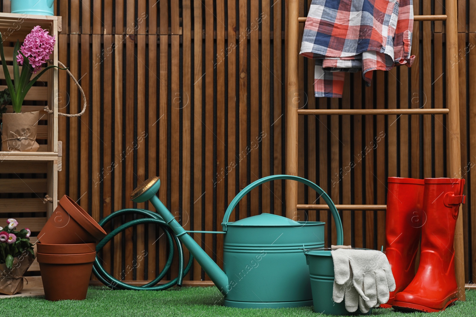 Photo of Composition with different gardening tools on artificial grass at wooden wall. Space for text