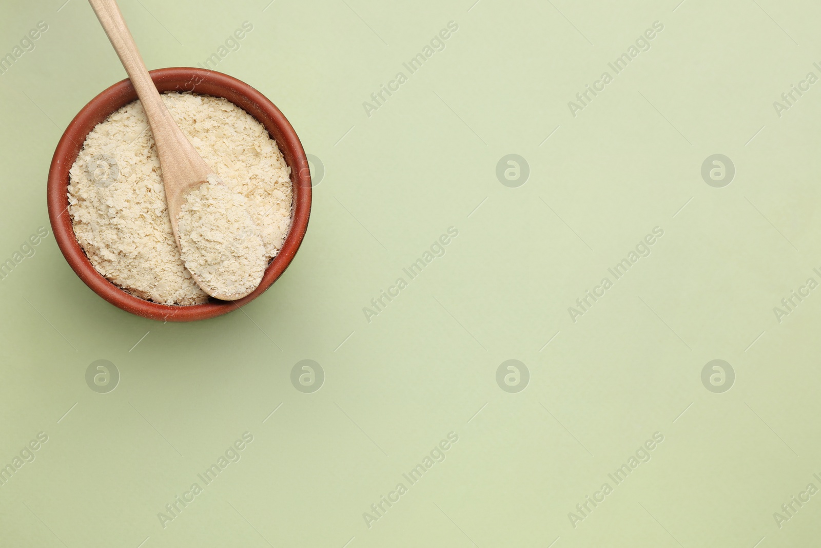 Photo of Beer yeast flakes on light green background, top view. Space for text