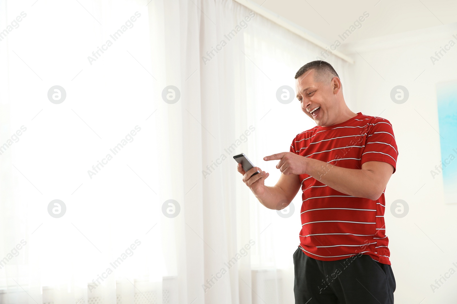 Photo of Portrait of emotional mature man with phone indoors. Space for text