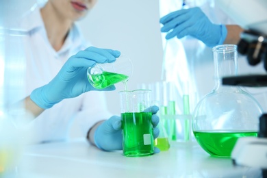 Scientists working with sample in modern chemistry laboratory, closeup