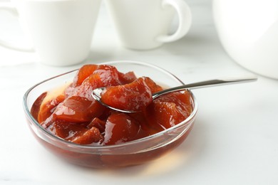 Quince jam in glass bowl on white table, closeup