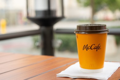 WARSAW, POLAND - SEPTEMBER 04, 2022: McDonald's hot drink on wooden table outdoors, space for text