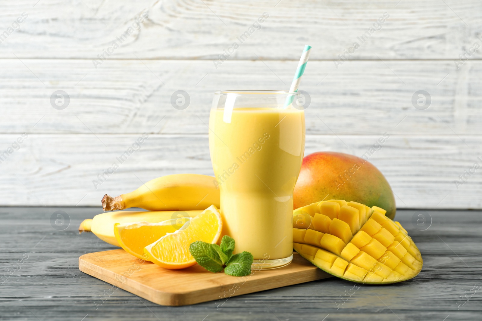 Photo of Tasty tropical drink with mango and fresh fruits on wooden table. Space for text