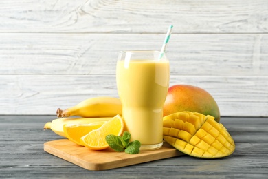 Tasty tropical drink with mango and fresh fruits on wooden table. Space for text