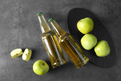 Photo of Delicious cider, whole and cut green apples on gray table, flat lay